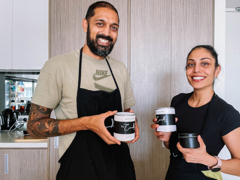 A couple holding up candles at a candle making class.