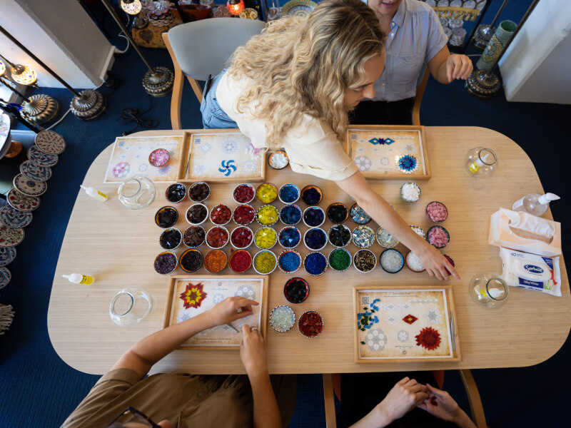 A top down shot of a group of people arranging colourful tiles into mosaics on a table