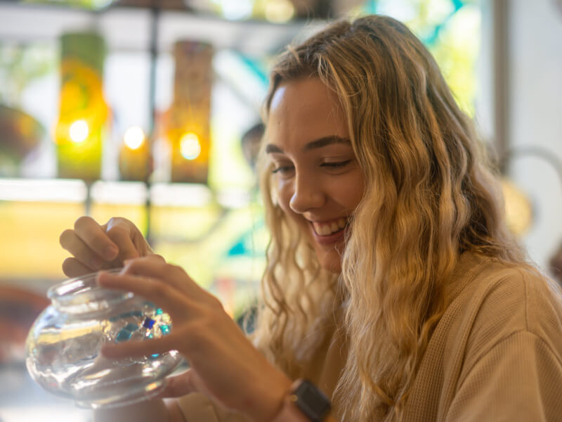 Woman smiling whilst making a mosaic lamp.