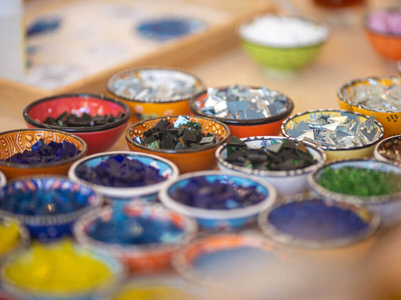 Several bowls filled with colourful glass to be used in making a mosaic.