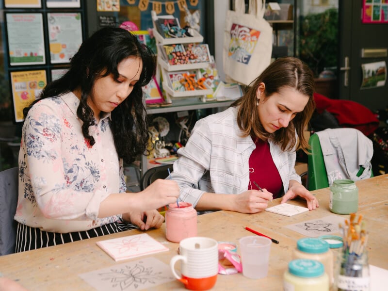 Two women painting pottery