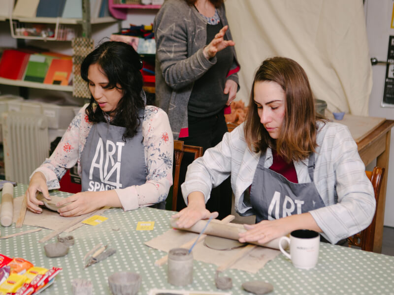 Two women handbuilding clay at a pottery class