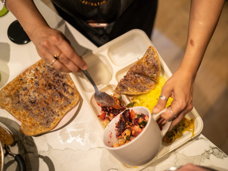 Hands serving a selection of vegan Indian food in a cooking class