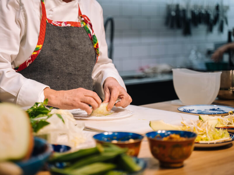 A close up shot of two hands arranging ingredients on a plate at a vegan cooking class