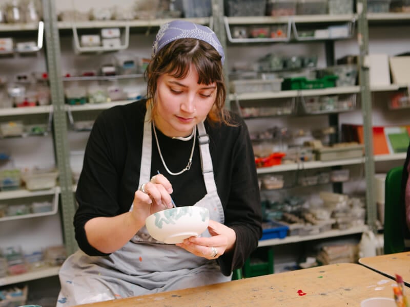 Woman wearing apron painting pottery