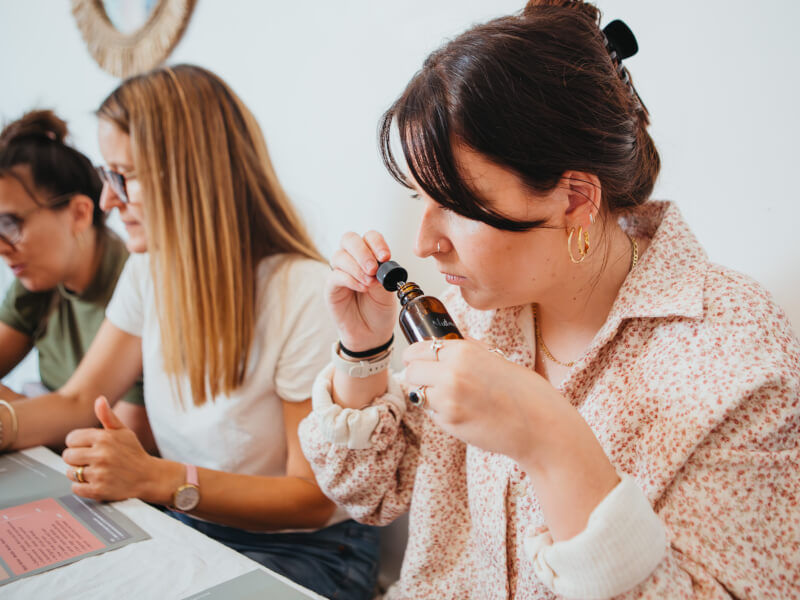 A woman at an aromatherapy rollerball class is smelling a dropper bottle of nutmeg oil