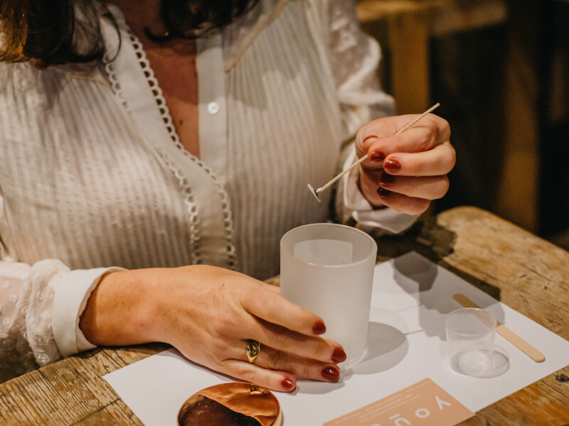 A woman placing a wick in a DIY candle.