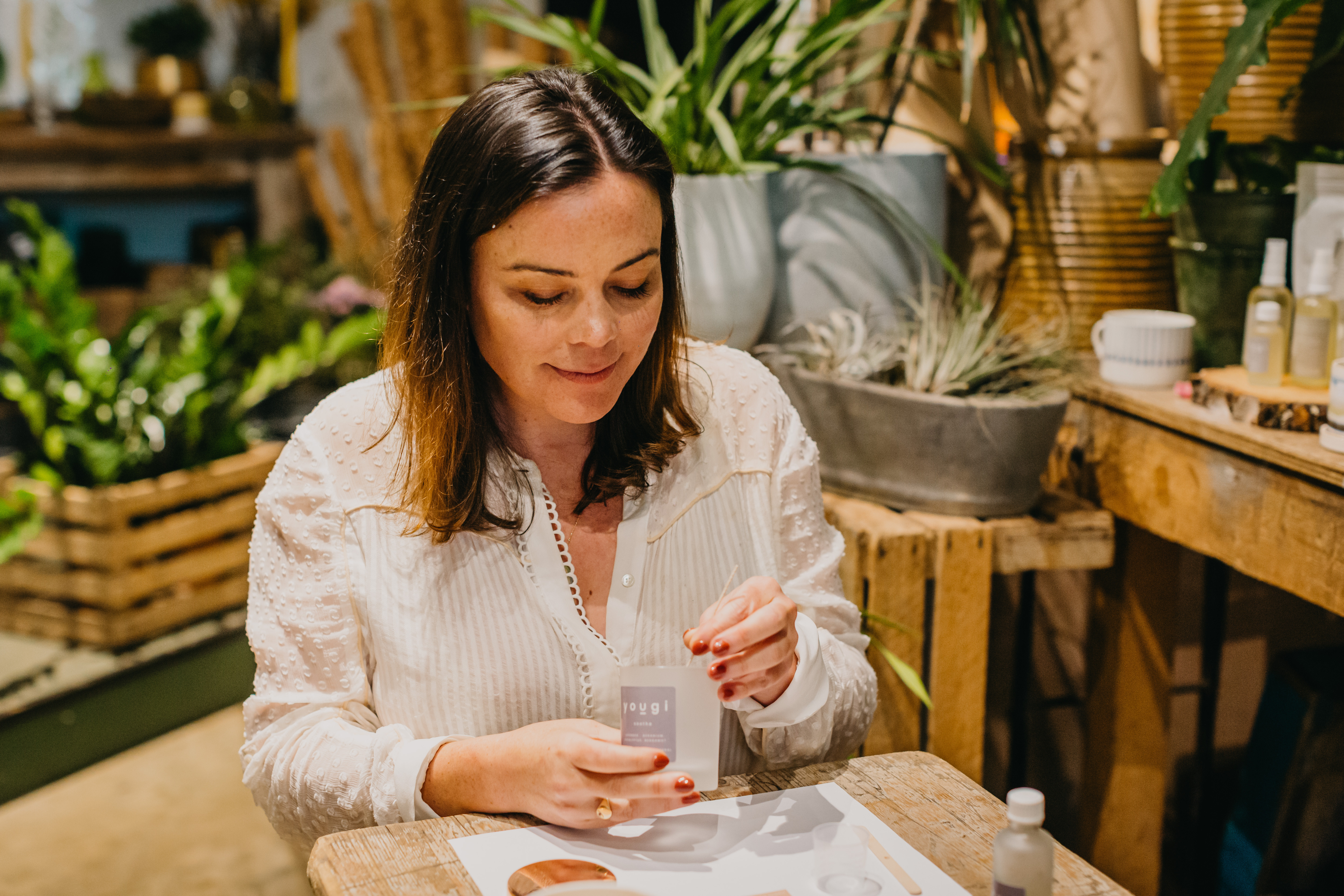 A woman in a white blouse making a small candle