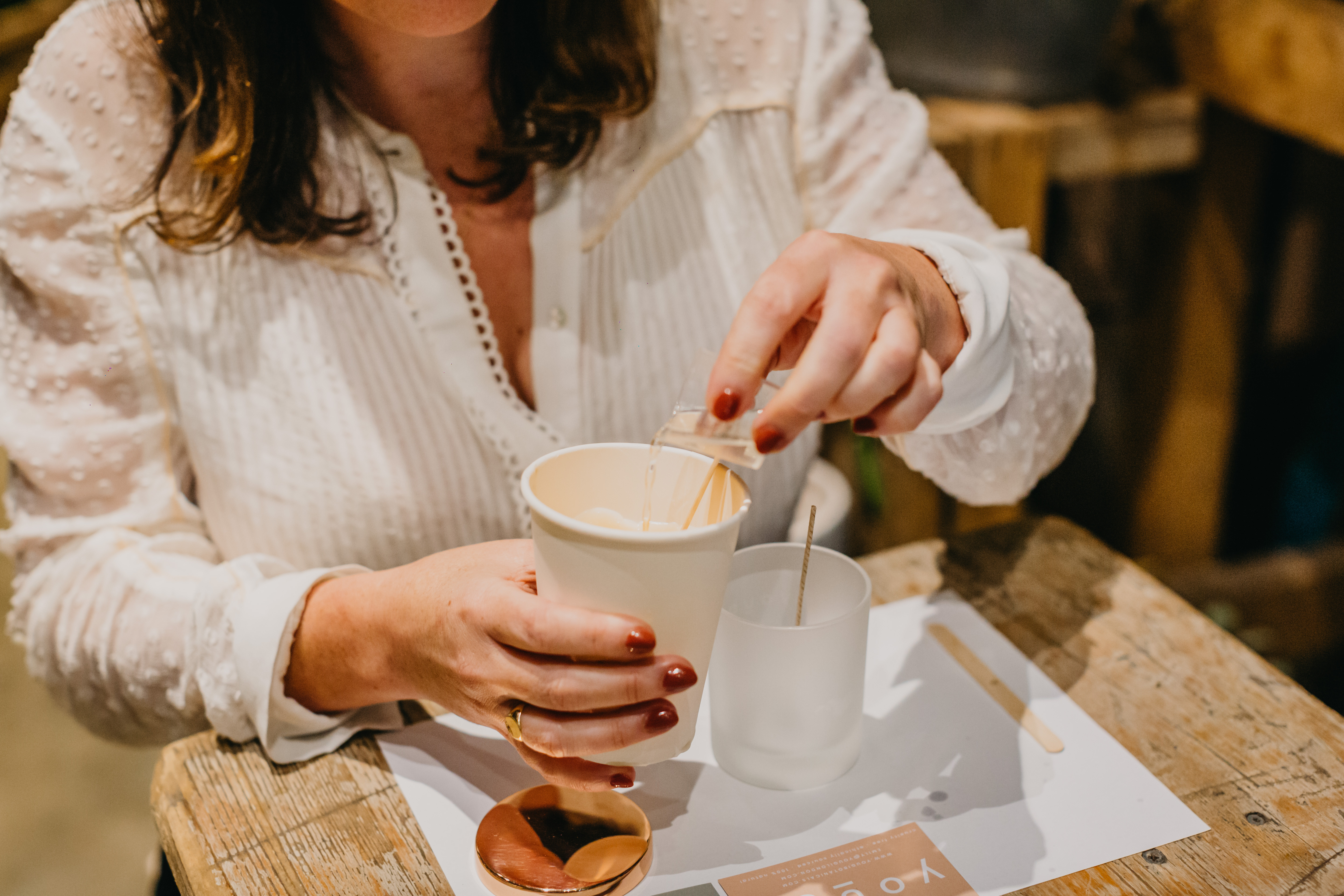 Close up of a woman in white blouse making a candle from scratch