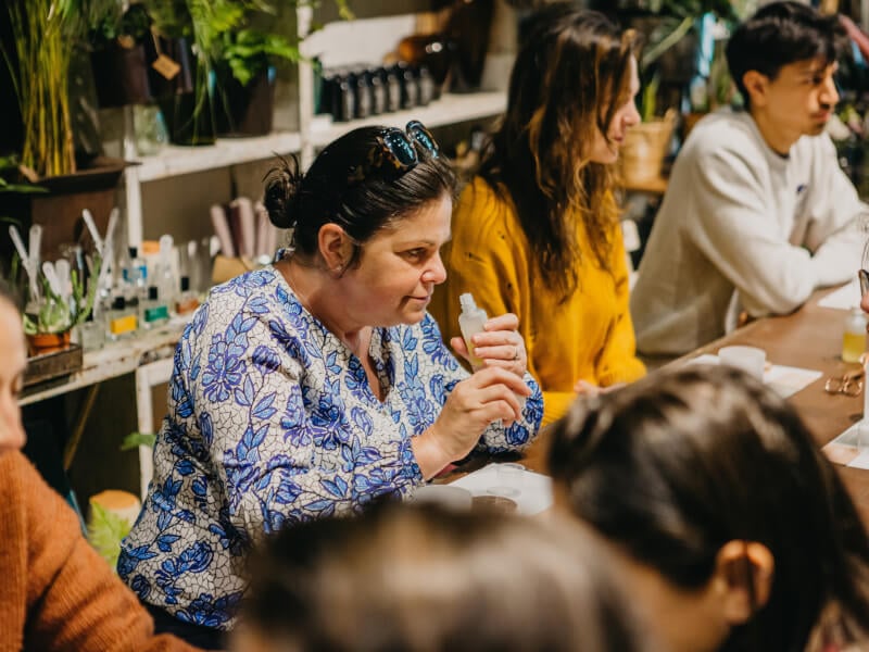 A woman sniffs a bottle of oil at a perfume making course.