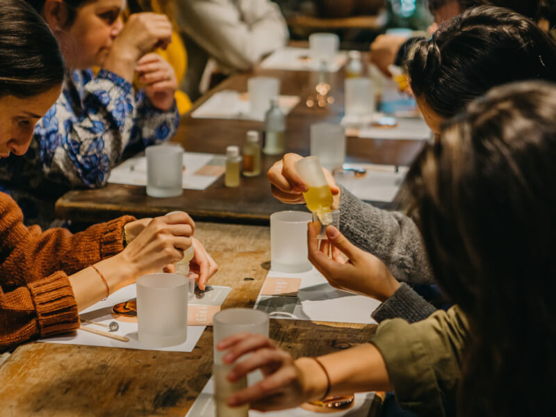 A group of students sit at a table enjoying a candle making classes