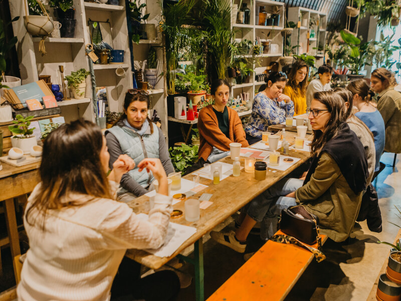 A group of people sit around a long table as they make candles together