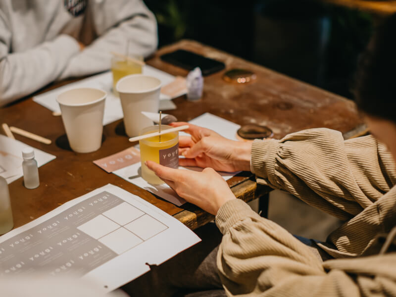 A woman holding a DIY soy candle at a candle making class.