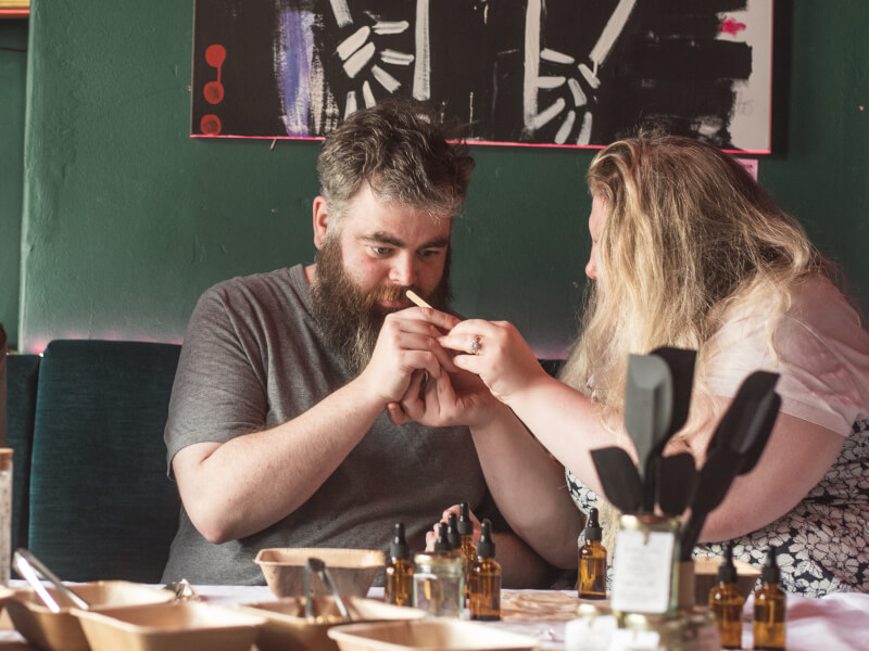 A man and woman are smelling essential oils at a candle making workshop