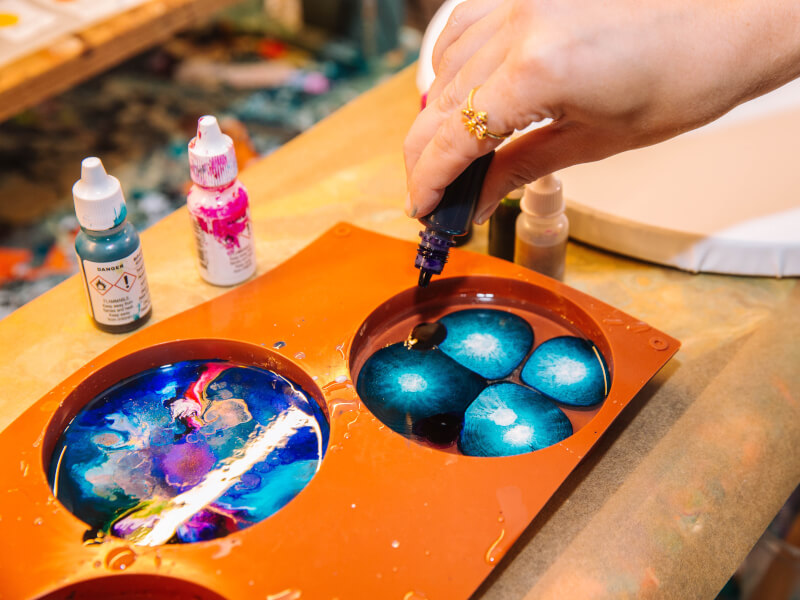 A close up of a tray of blended and mixed paint in blue, white, pink and purple, ready for paint pouring