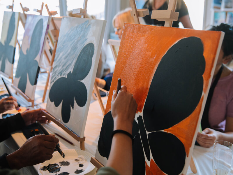 A group of people painting abstract pictures on canvas at a painting class
