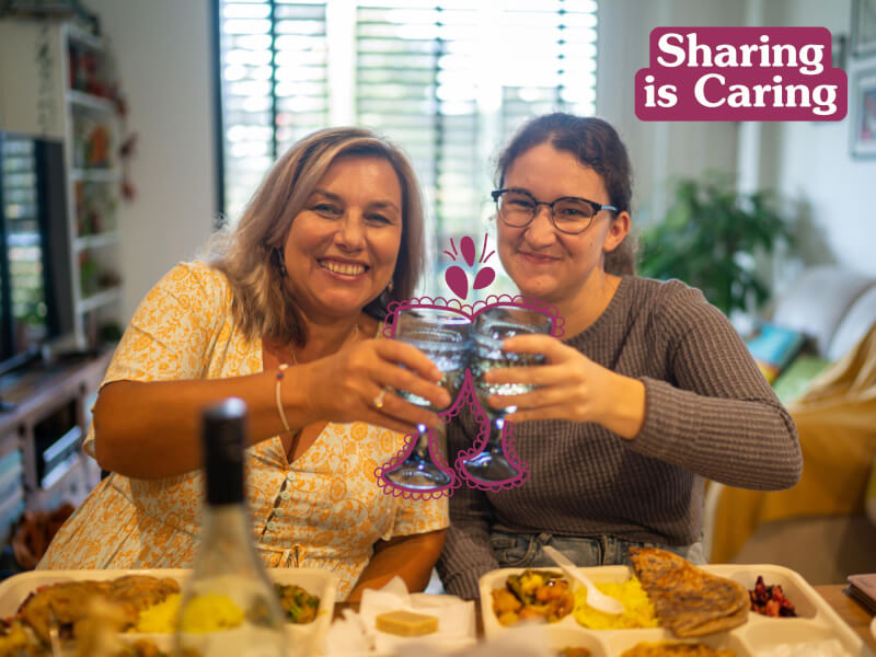 Two friends clink classes at a dinner party.