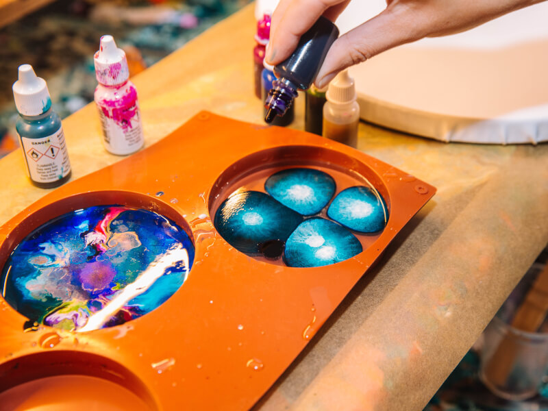 A pallette with brightly coloured paint creating a marbled pattern sits on a table.