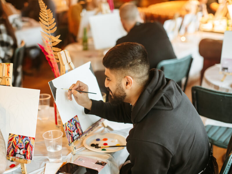 A close up of a person sketching a picture of a lion onto a canvas ready for acrylic painting
