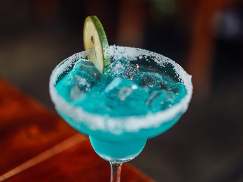 A bright blue DIY cocktail in a margarita glass.