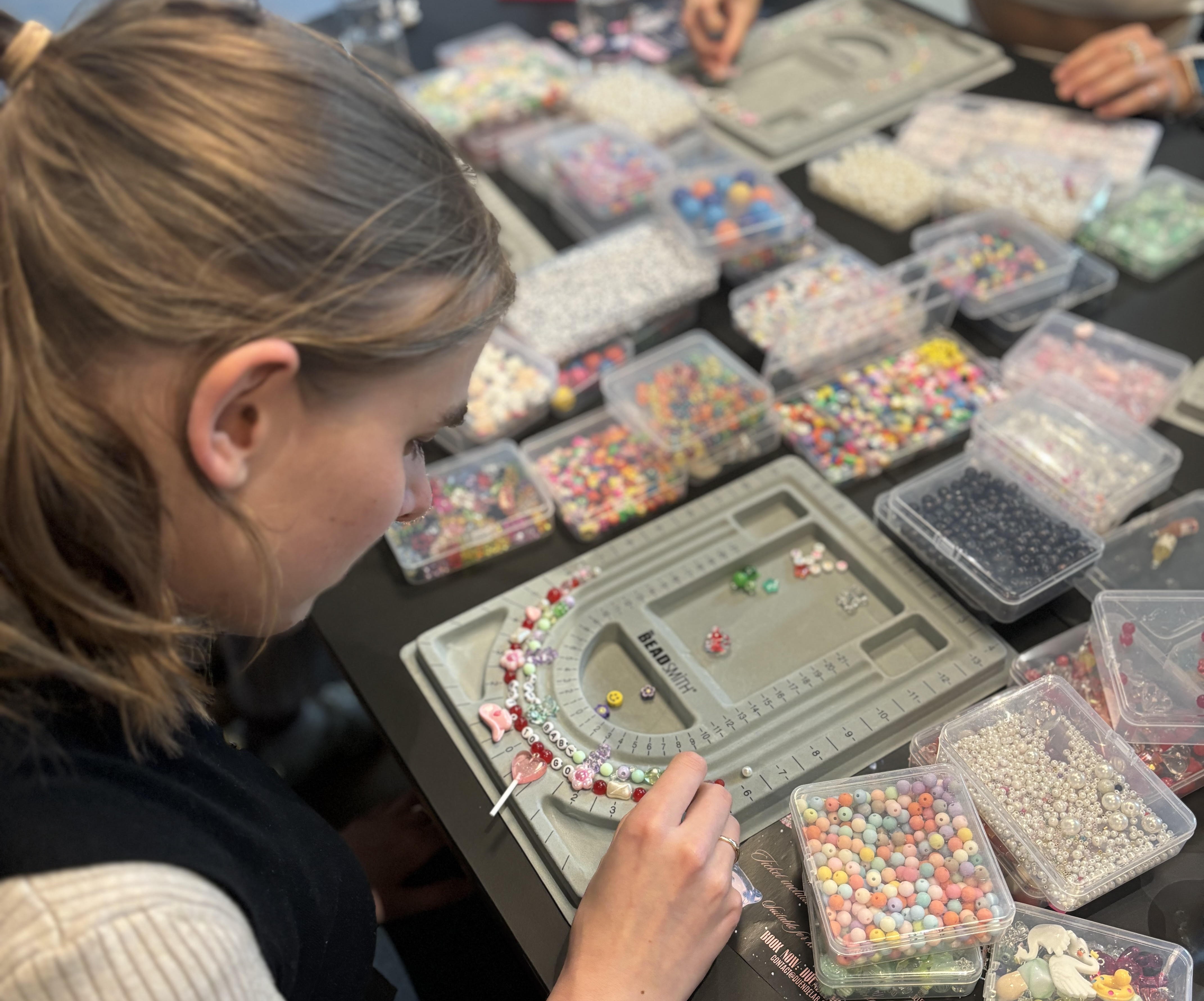 Woman using beads to make a necklace in a jewellery making class