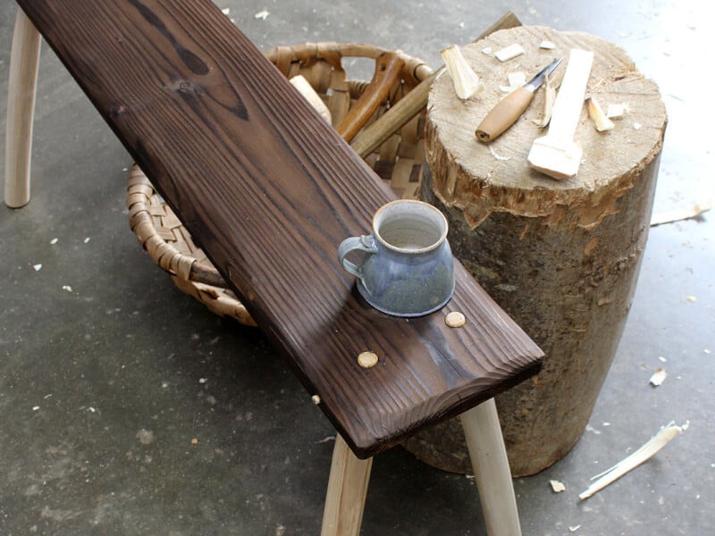 A ceramic cup sits on a handmade wooden bench in a woodwork workshop