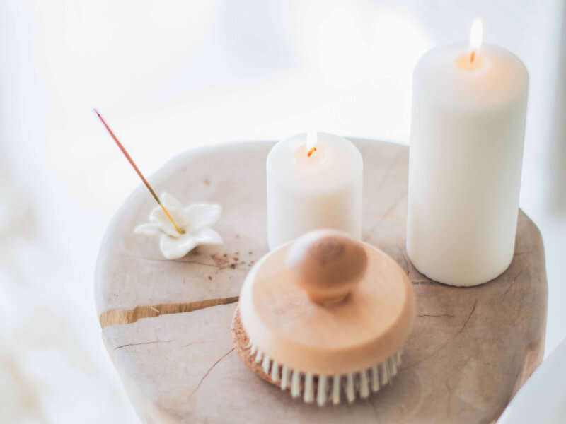 Two lit homemade candles next to an incense stick
