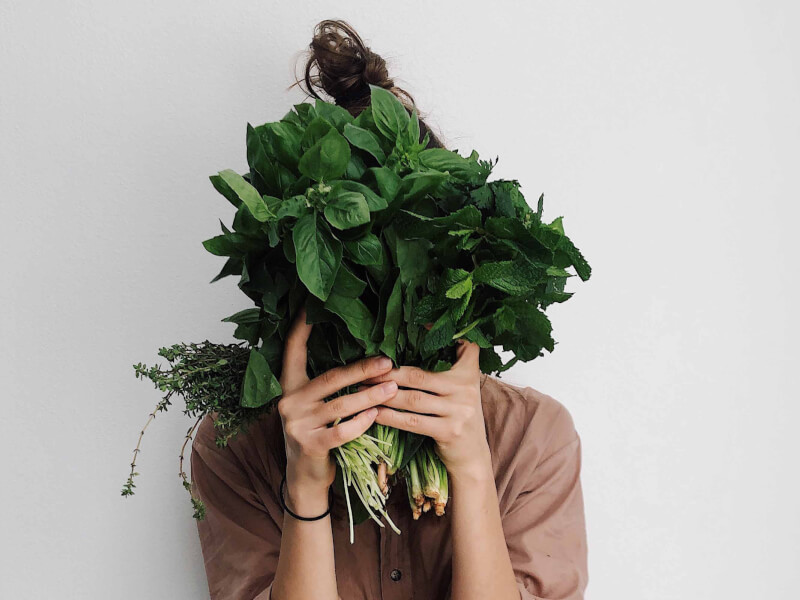 A person holiding up fresh herbs and plants