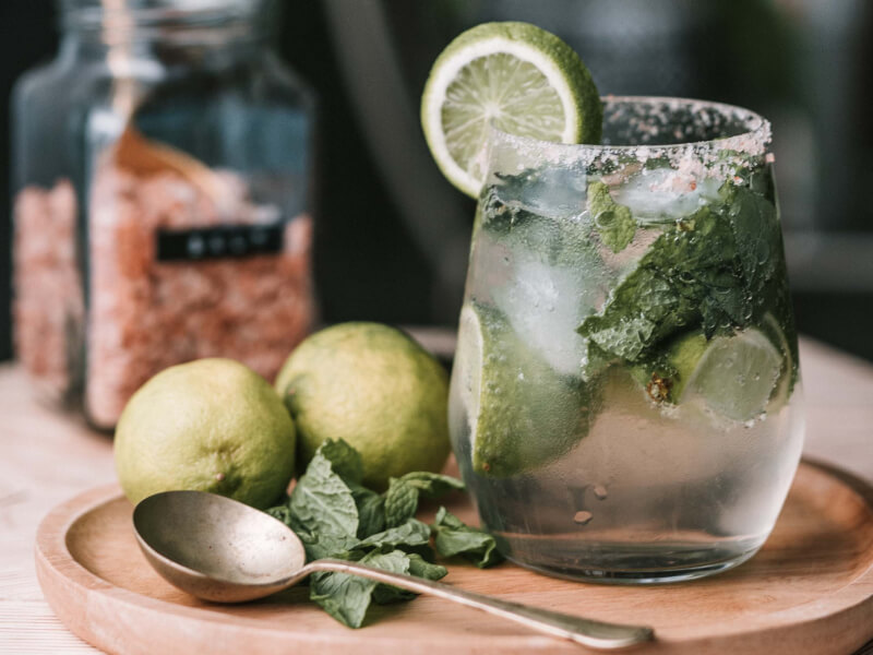 A cocktail in a glass flavoured with herbs and a lime