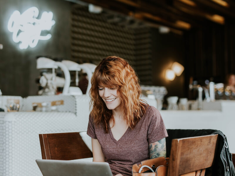 Office worker with laptop sits in a cafe to partake in an online class.