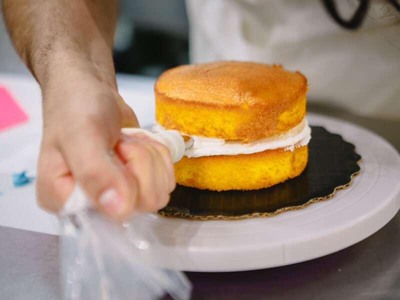 Hand putting icing on a cake in a baking class