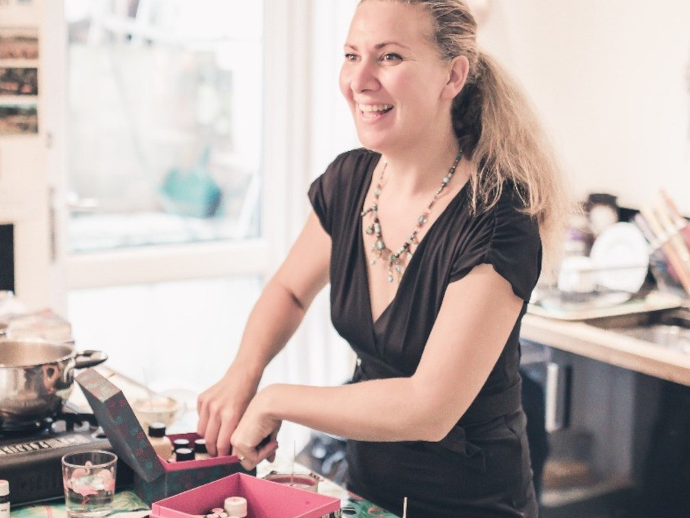 A woman smiling whilst making candles from a kit