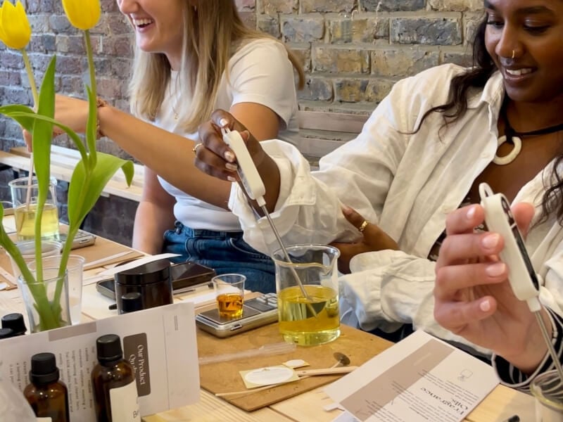 Two women are laughing and making candles at a candle making class