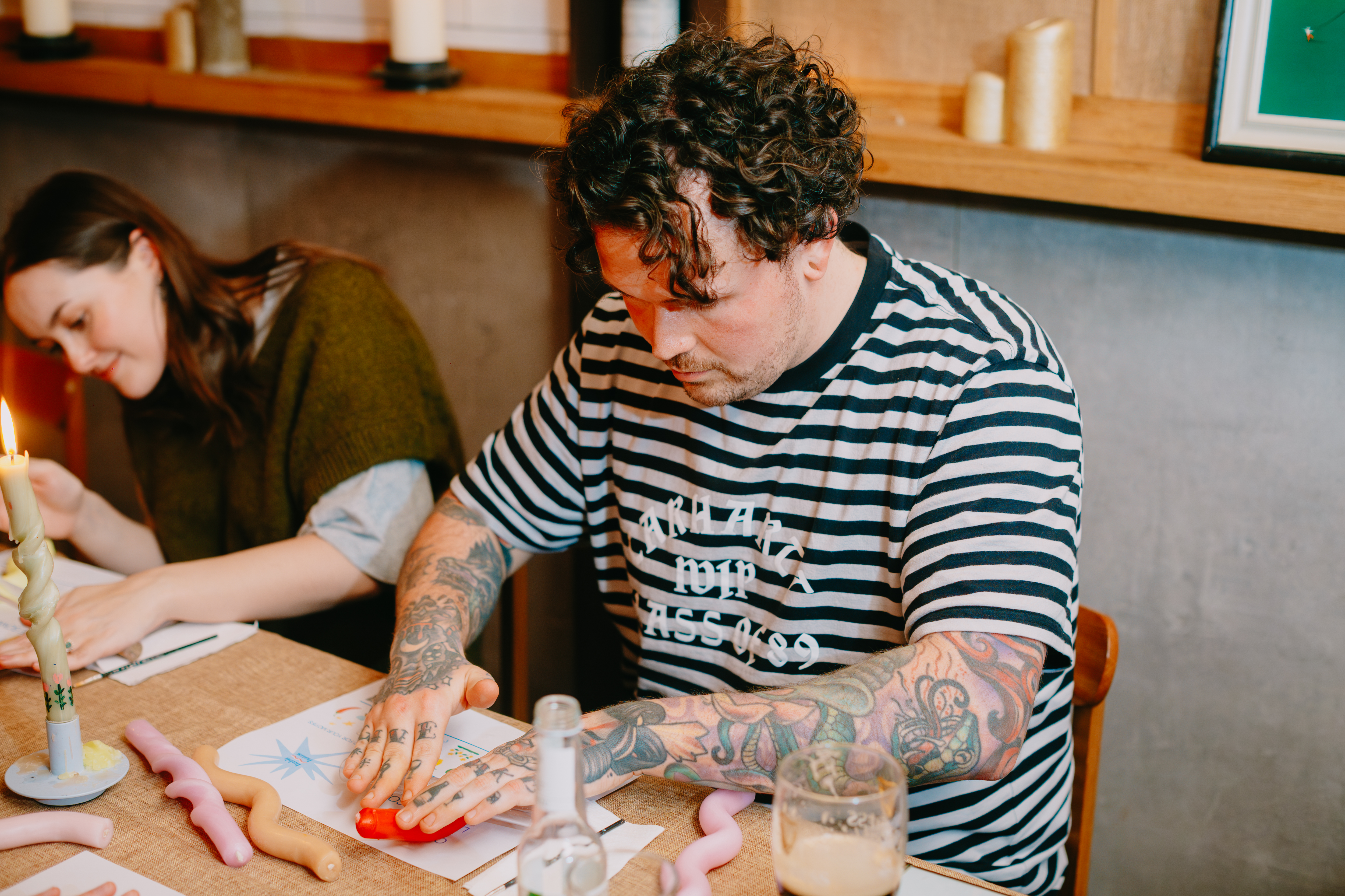 A man is making bendy candles by rolling them on the table