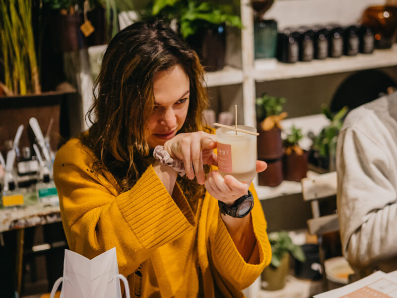 A woman at a candle making experience is levelling the wax in her jar