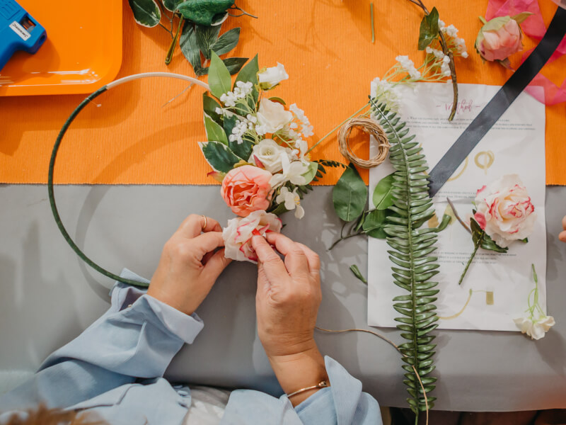 A top down shot of a person attaching flowers to a floral hoop