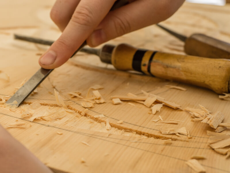 A person is wood carving an object out of a big block of wood.