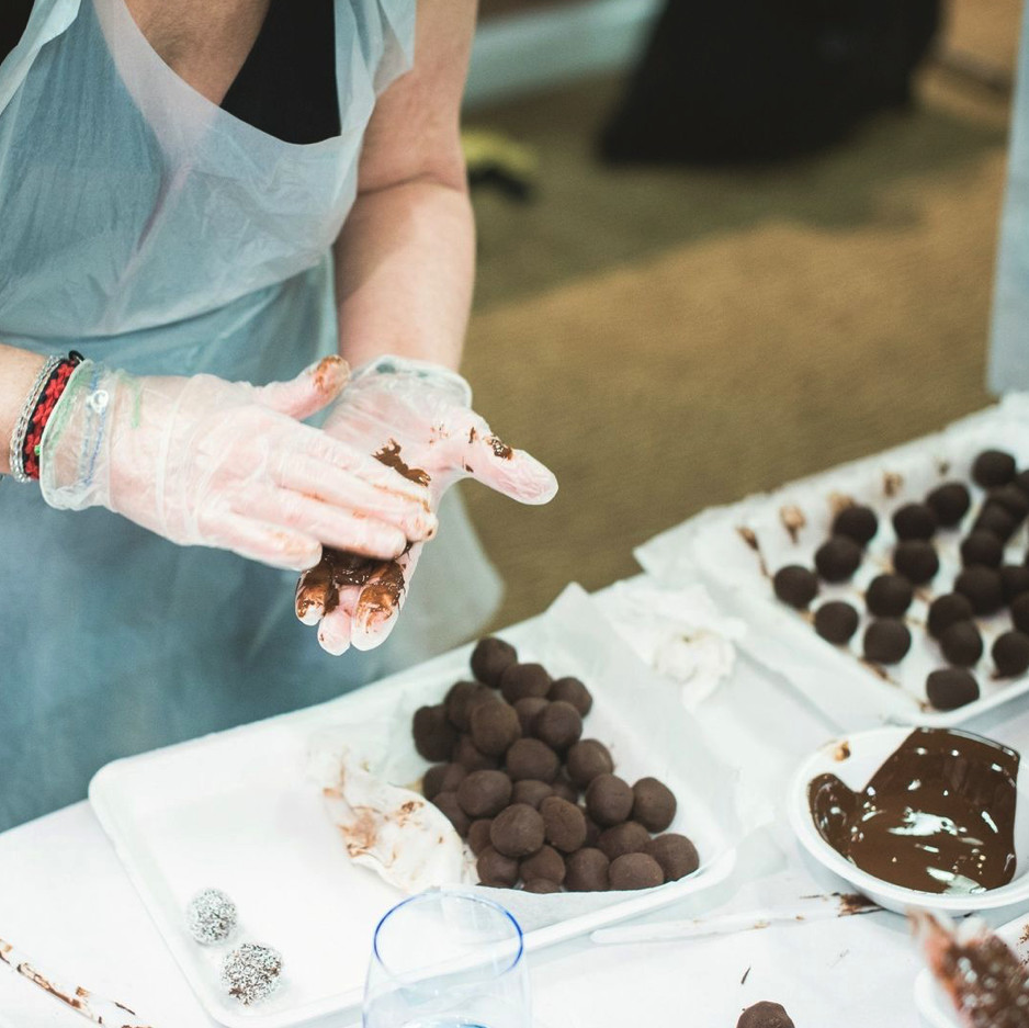 Close up of a person with nitrile gloves rolling chocolate truffles