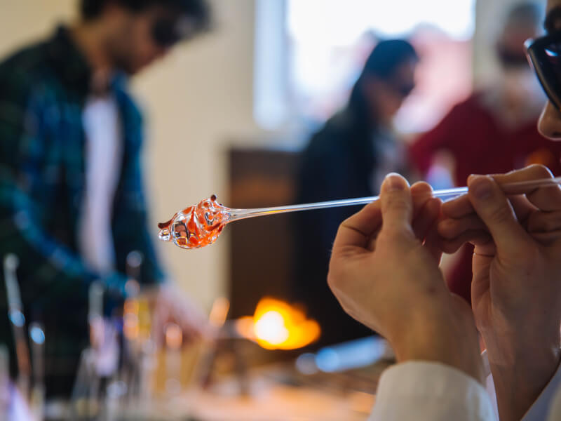 A close up of a person blowing glass into a shape