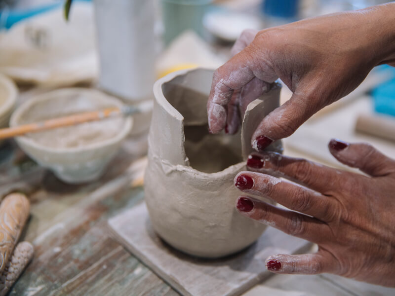 A close up of a person making a cup from clay using hand building techniques