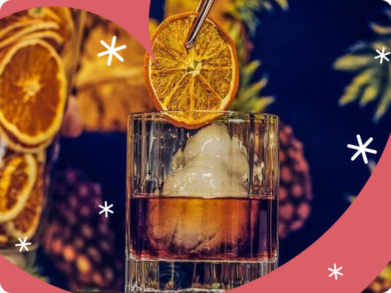 A close up of a person adding a slice of orange to a glass filled with ice