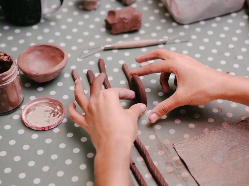 A close up of a person making a coil pot using hand building pottery techniques