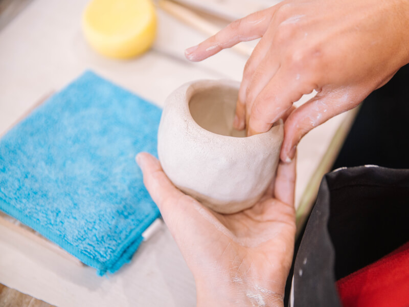 Close up of hands making a clay pinch pot