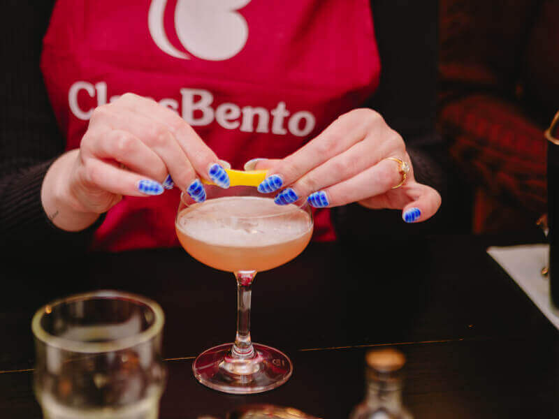 Hands squeezing a lemon into a cocktail in a cocktail class