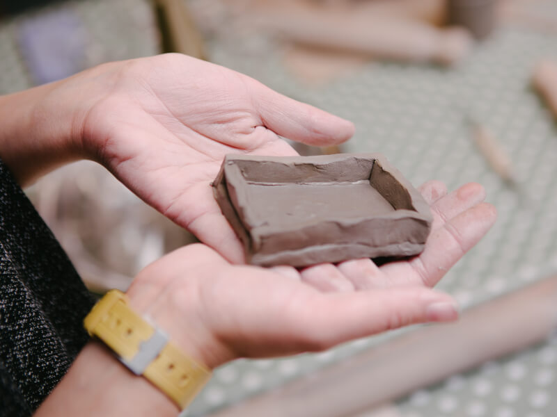 A close up of a square coil pot in someone's hand