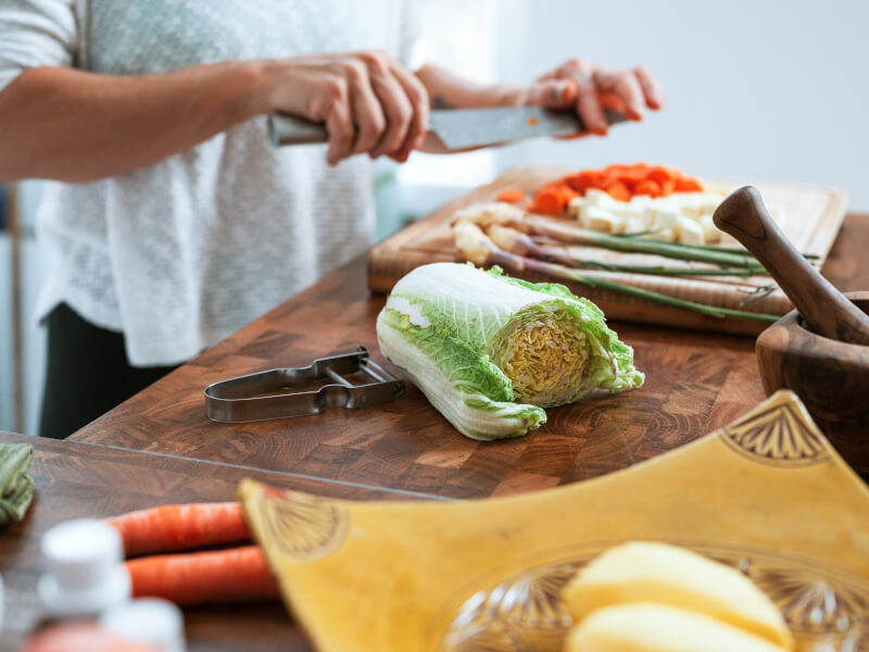 A person is chopping vegetables on a wooden table