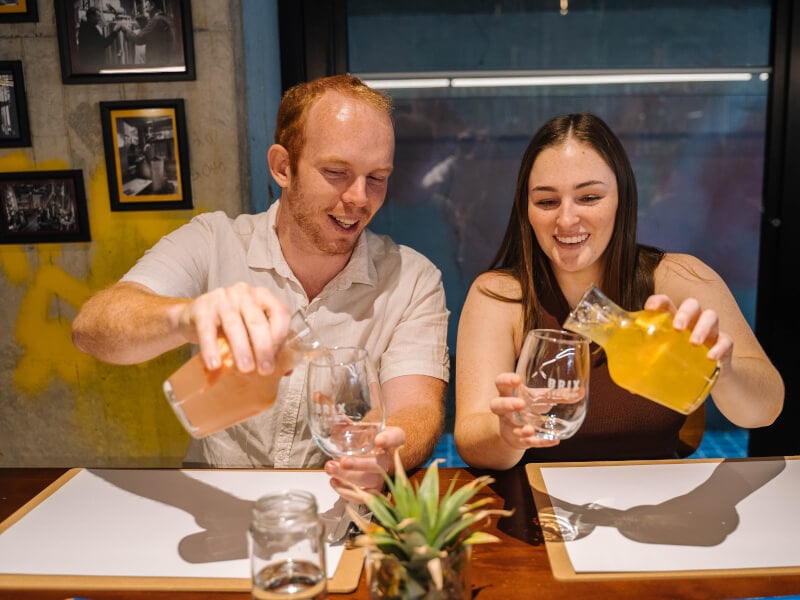 Man and woman pouring drinks in a sip and paint class
