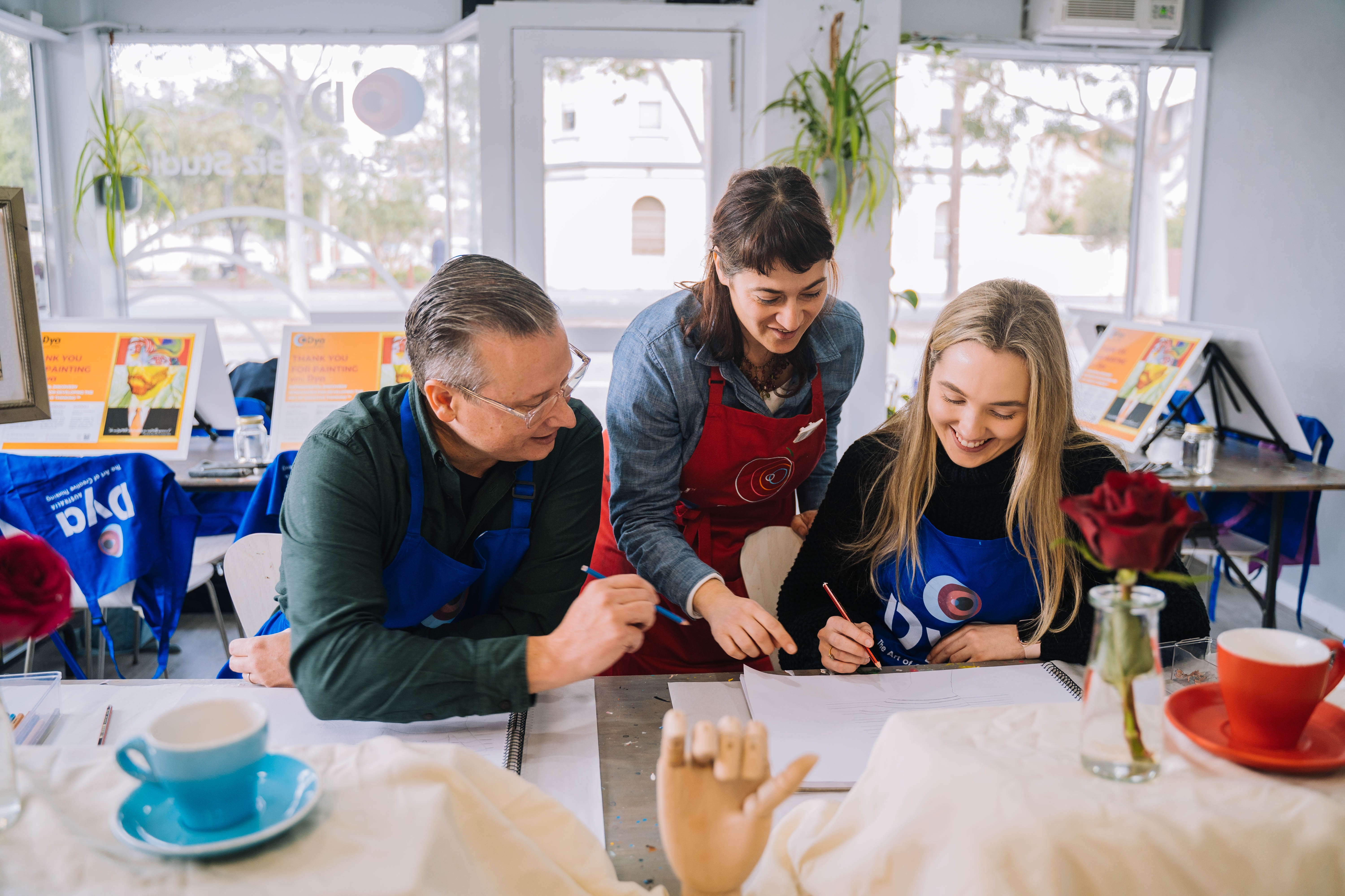 A couple are being taught to paint by an art teacher