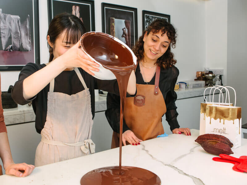 Smiling couple pouring melted chocolate in a chocolate class