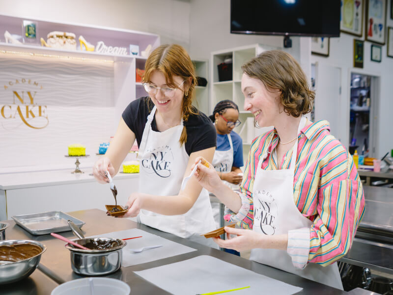 Two women pouring melted chocolate